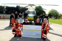 Jay Webb and Sharon Todd present a cheque to Fred Thompson and Keith Mills of Wiltshire Air Ambulance watched by scooter club members. Picture by Siobhan Boyle