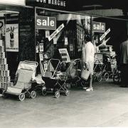 Bulky prams and pushchairs parked outside the new Bon Marche department store about half a century ago