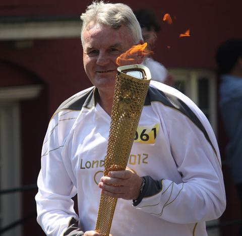 Your flame to fame. 
Readers' pictures capture memories of the Olympic Torch in town.
retired Swindon PE teacher Ian Perkins, 59, carries the torch into the High Street at Marlborough