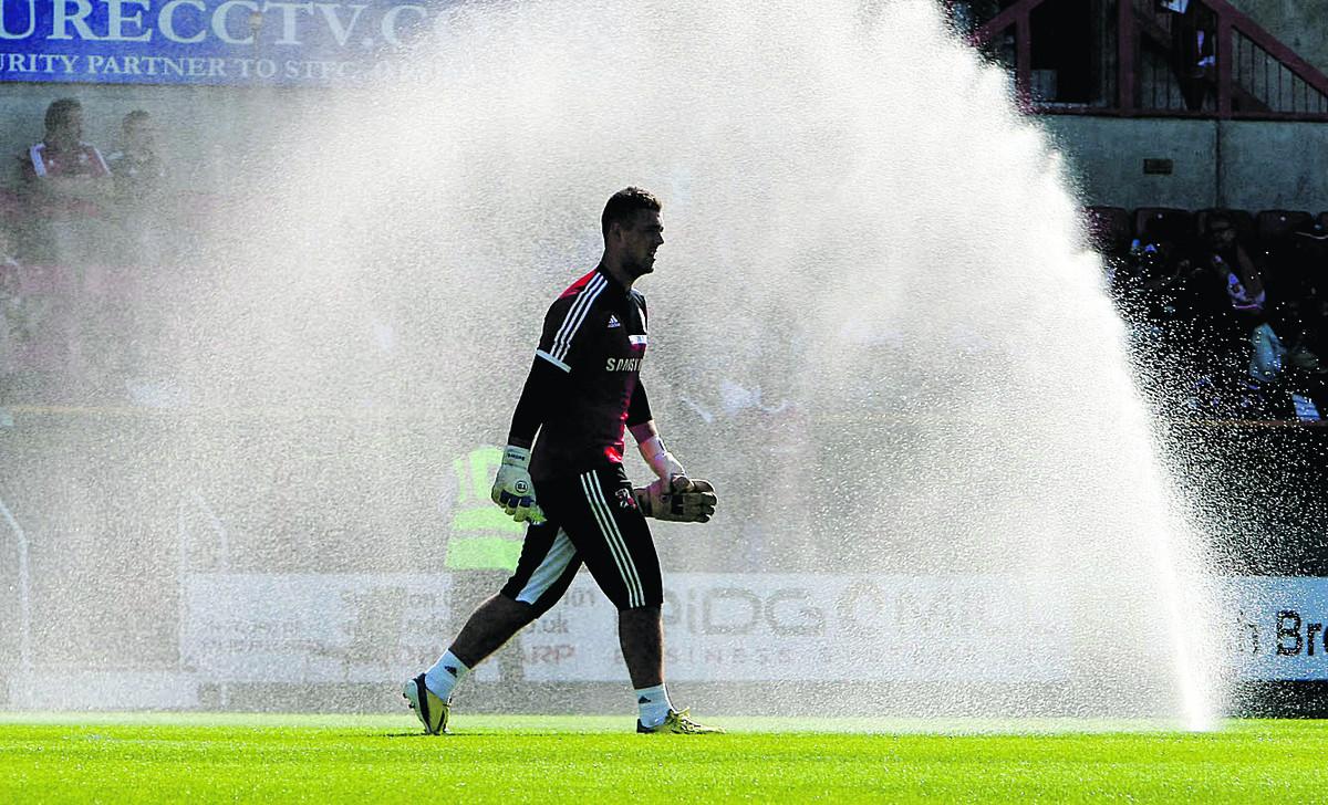 Swindon Town reserve goalkeeper Tyrell Belford makes a splashing entrance by the sprinklers during the team warm-up before Saturday’s game with Crewe