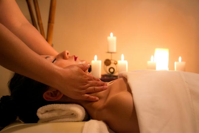 A woman getting a massage in a candle-lit spa. Credit: Canva