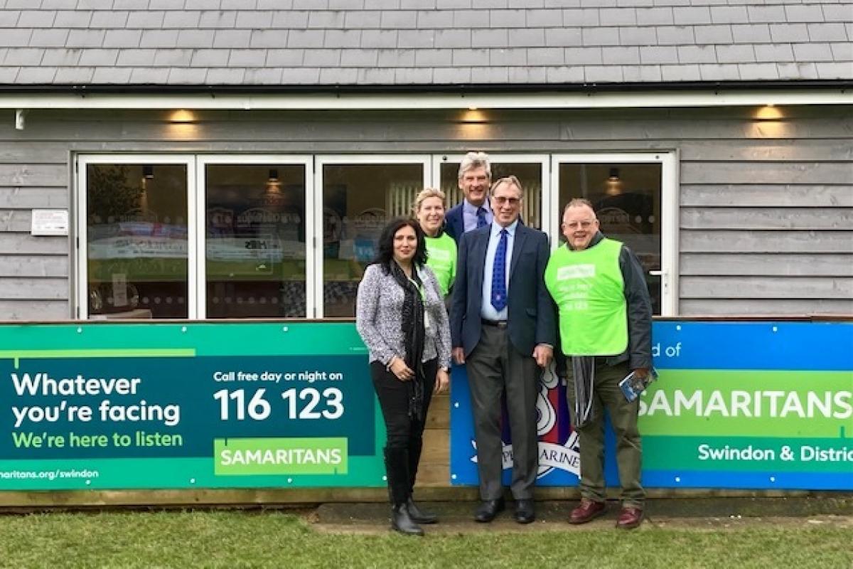 A couple of volunteers from Samaritans alongside Swindon Supermarine club president Steve Moore (second from right) and the new advertising boards at the Webbswood Stadium