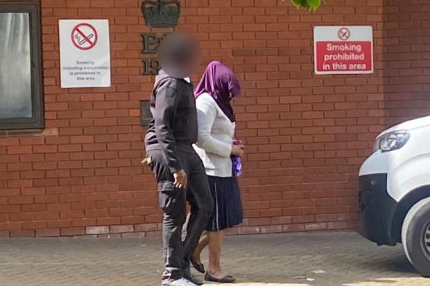 Ivy Mwangi with her head covered being escorted out of Swindon Crown Court