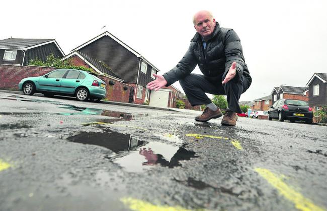 John MacClay next to a pothole