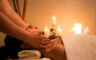 A woman getting a massage in a candle-lit spa. Credit: Canva